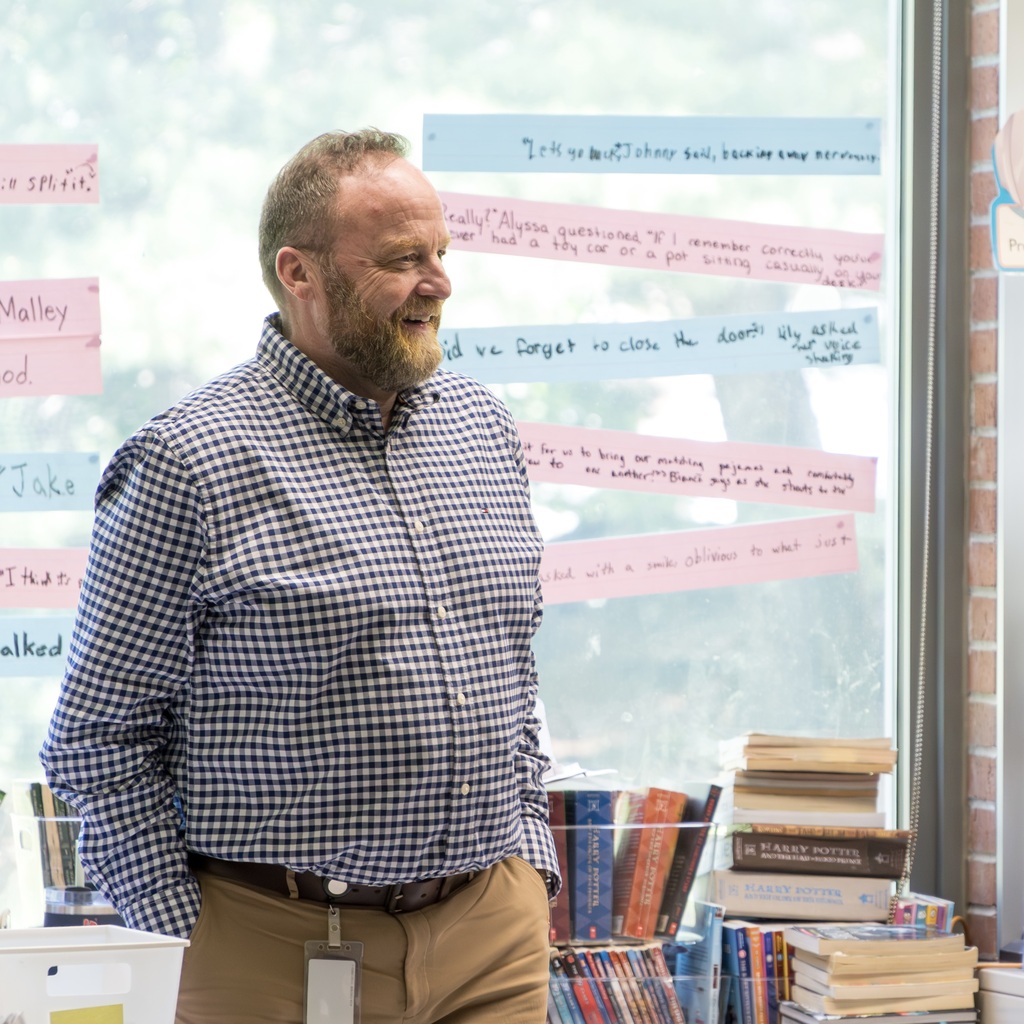 Directo of Special Education John Fletcher stands in front of a glass wall with colorful post-it notes.