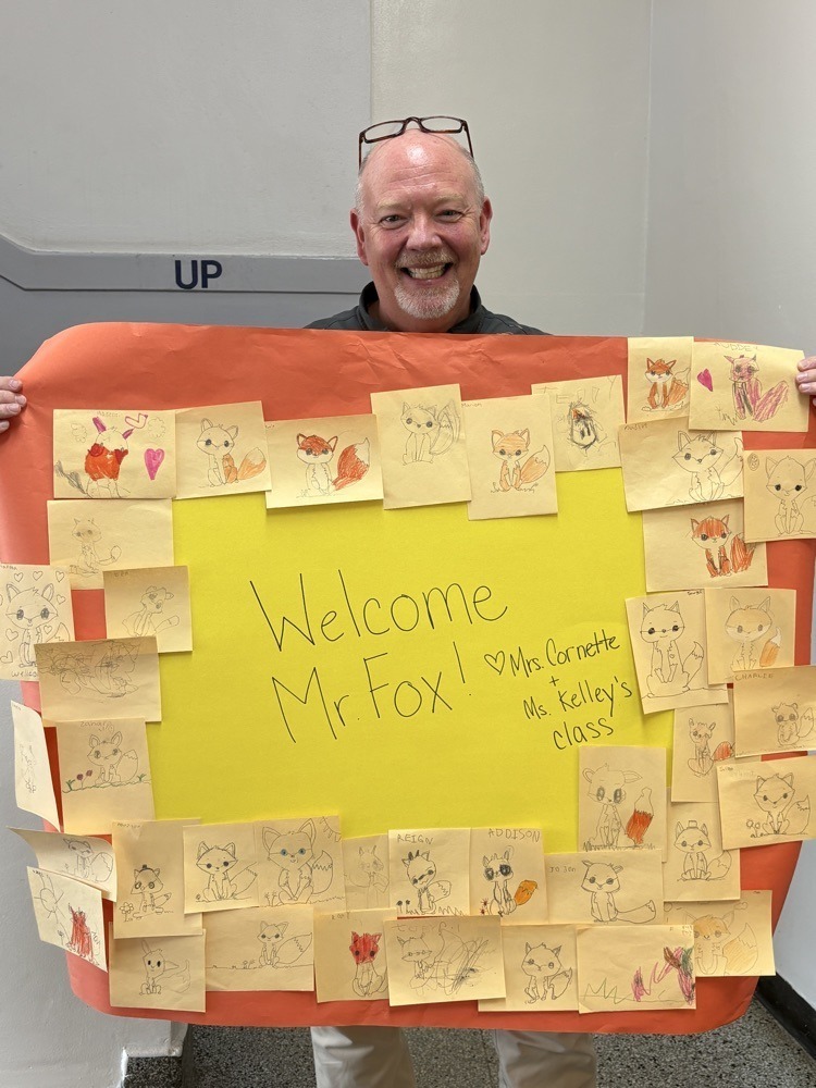 Mr. Fox holding students drawings of a fox.
