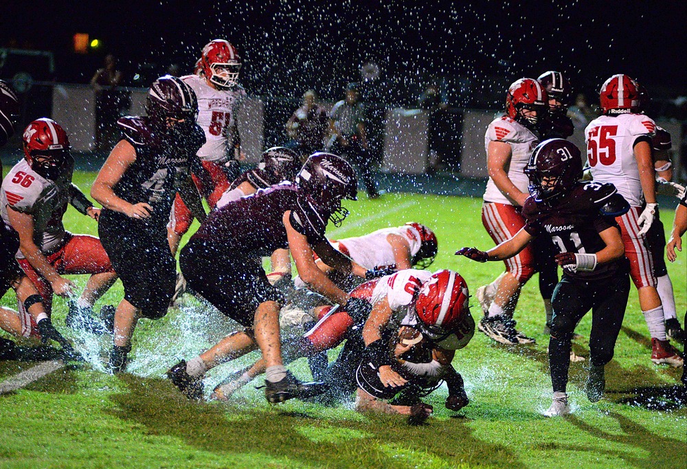 Marshall QB Luke Brodie runs over a Robinson defender in damp field conditions during the Lions' win
