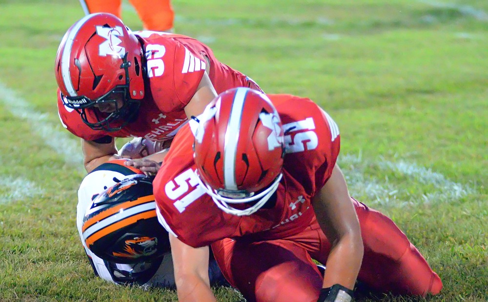 Josef Stafford (51) and Fisher Bishop (55) make a Tiger sandwich while bringing down an Olney ball cafrrier for a loss