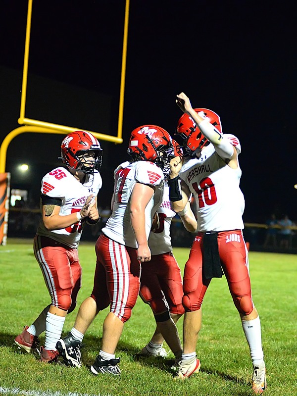 Marshall players celebrate Wyatt Geltz (center) scoring on a two-point conversion for the Lions to take the lead in the 3rd quarter at Paris