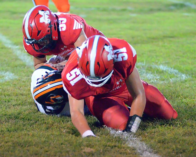 Josef Stafford (51) and Fisher Bishop (55) make a Tiger sandwich while bringing down an Olney ball cafrrier for a loss