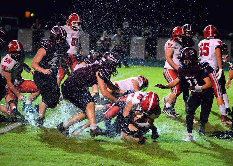 Marshall QB Luke Brodie runs over a Robinson defender in damp field conditions during the Lions' win