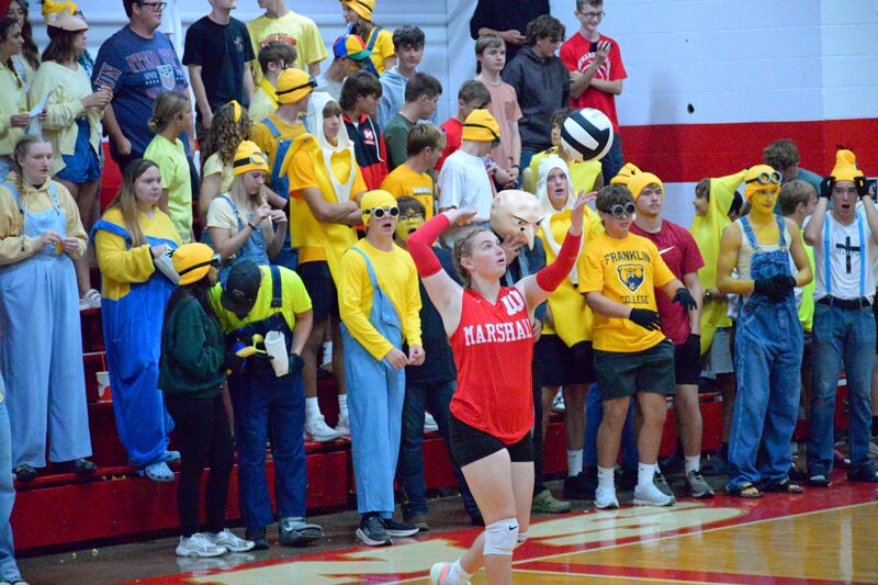 Ellie Delp serves the ball as Gru and his Minions look on