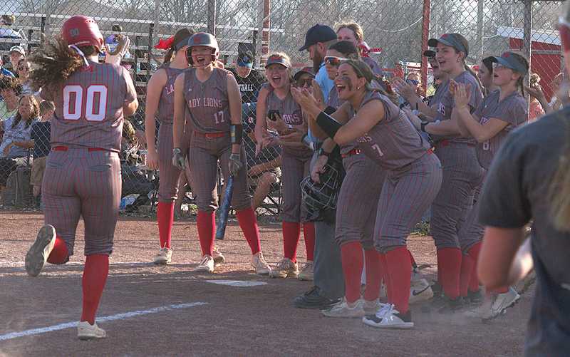 Marshall's McKenzie Davis (00) is greeted at home plate by her teammates after smashing a home run against Hut-Pal