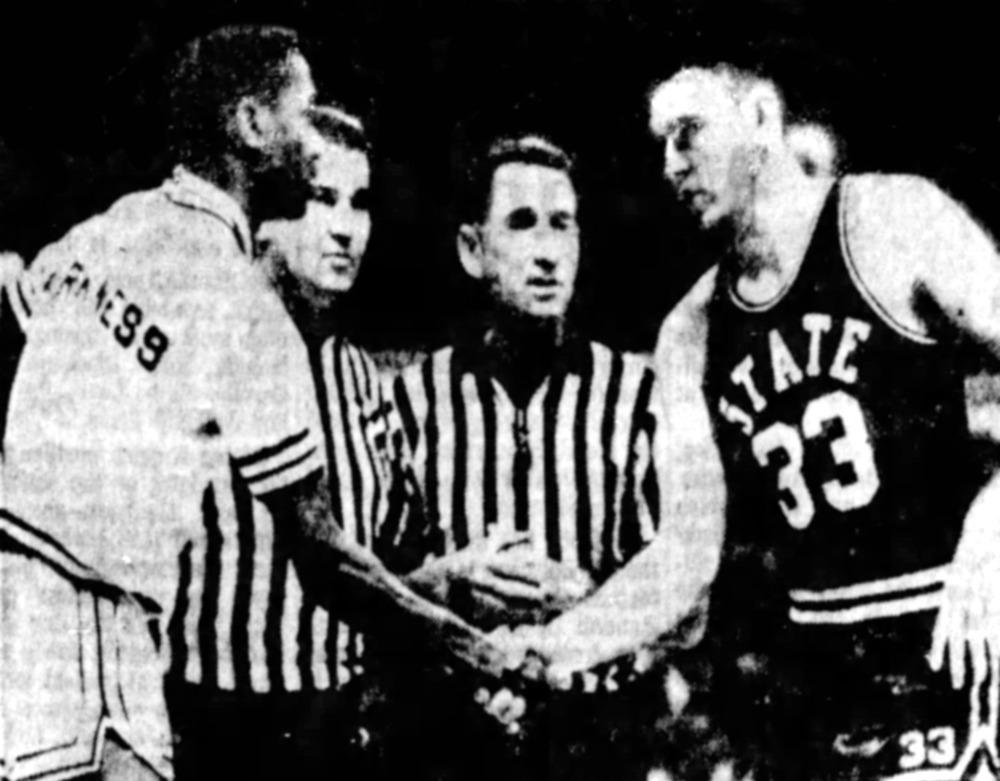 Picture of Joe Dan Gold and black basetball player shaking hands at midcourt just before tip-off in basketball game