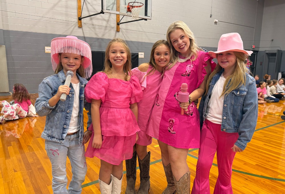 Photo of CCES students and teach in gym dressed in pink and cowboy boos in honor of Dolly Parton