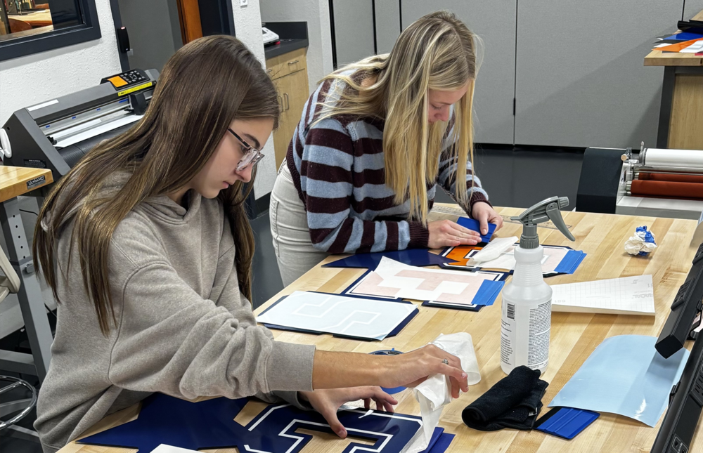 2 students workng on custom signs for CES