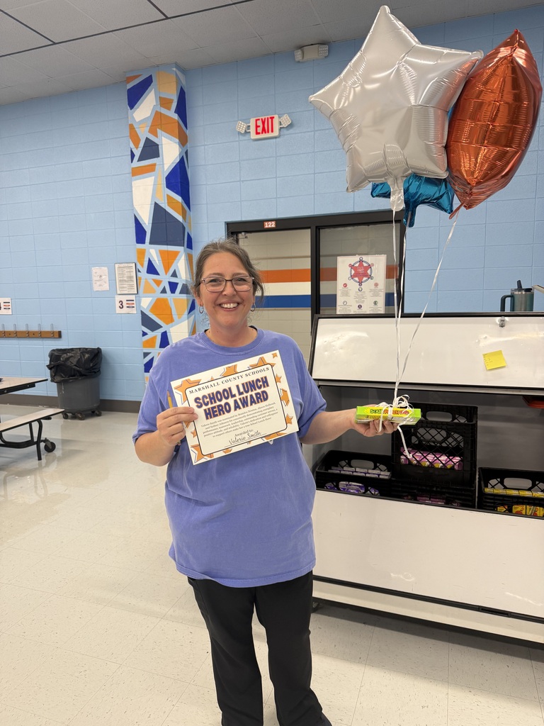 Photo of Valerie Smith in cafeteria holding balloons and her school lunch hero award
