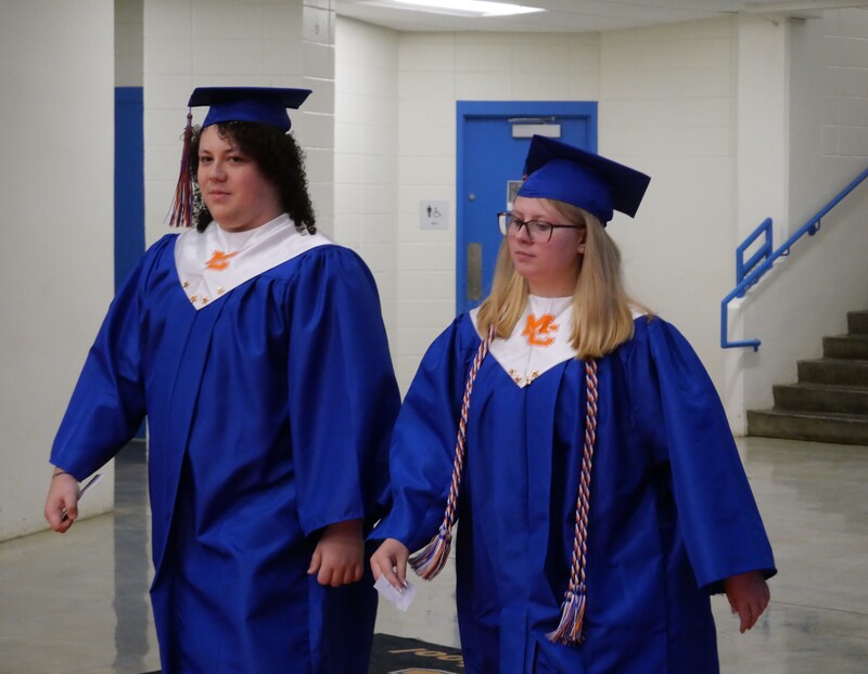 Graduates walking onto gym floor for graduation ceremony