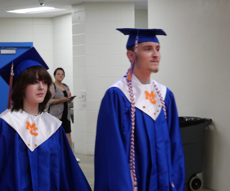 Graduates walking onto gym floor for graduation ceremony