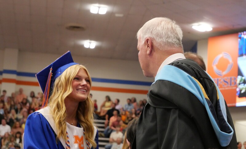 Graduate walking across stage to receive diploma