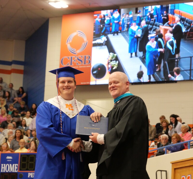 Graduate walking across stage to receive diploma