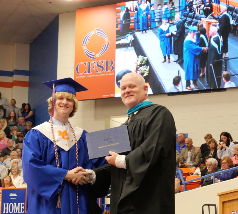 Graduate walking across stage to receive diploma