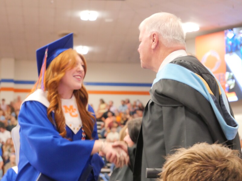 Graduate walking across stage to receive diploma