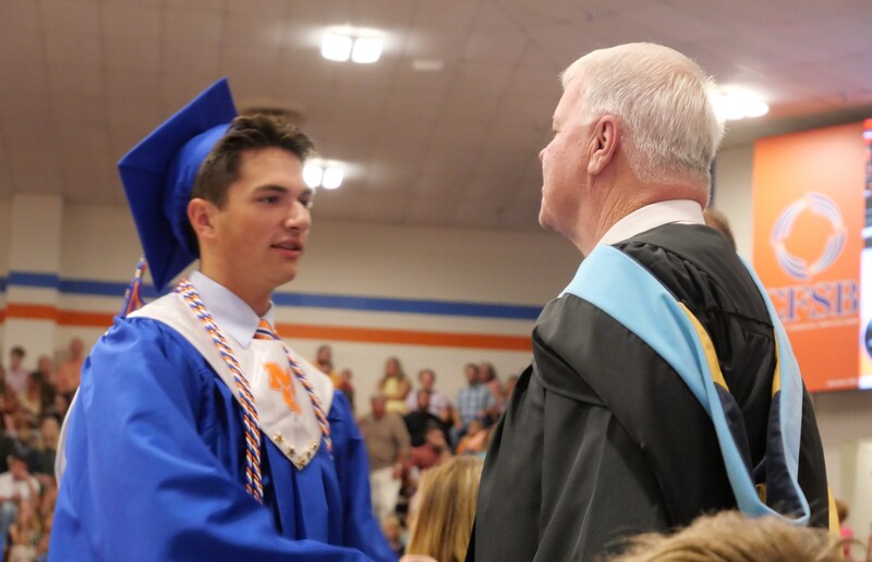 Graduate walking across stage to receive diploma