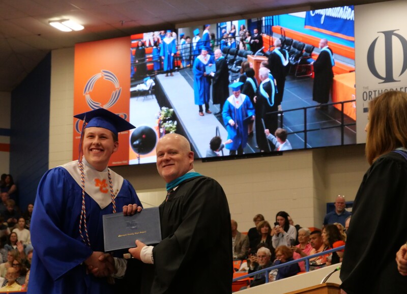 Graduate walking across stage to receive diploma