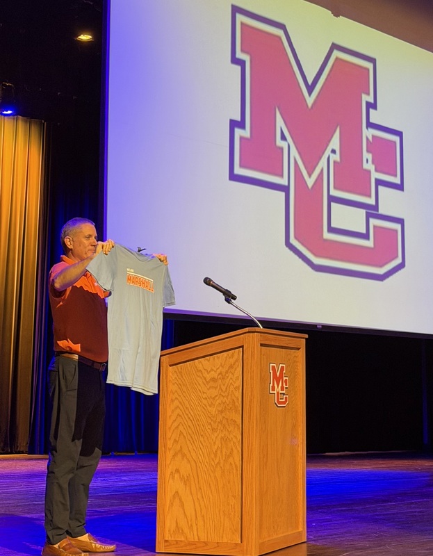 CFSB president Jason Jones on PAC stage holding up snew staff t-shirts
