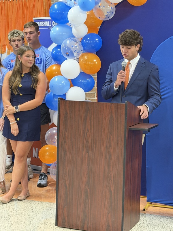 Students speaking at podium during Marshall Merch grand opening