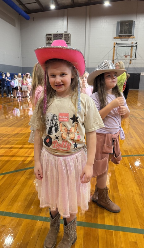 Photo of CCES student in gym dressed in pink cowboy hats in honor of Dolly Parton