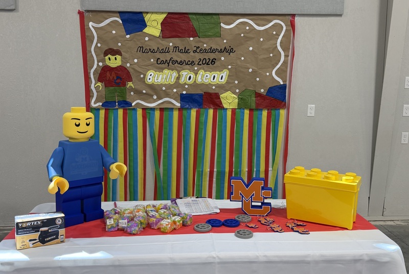 Table with Legos and theme "Built to Lead" on wall behing table