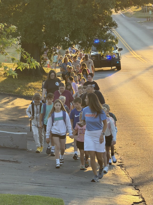 Group of walkers make their way up sidewalk for International Walk to School Day