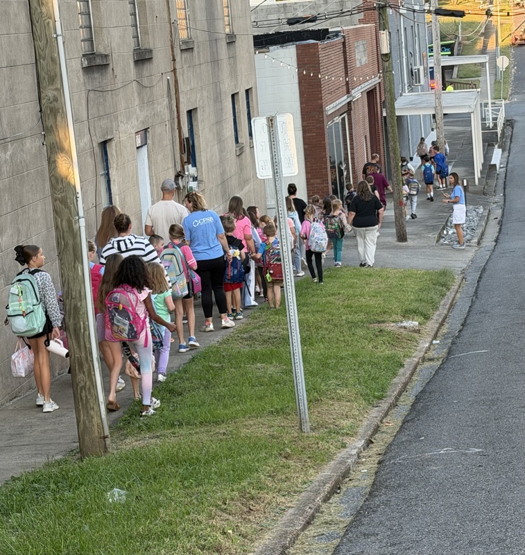 Group of walkers make their way up sidewalk for International Walk to School Day