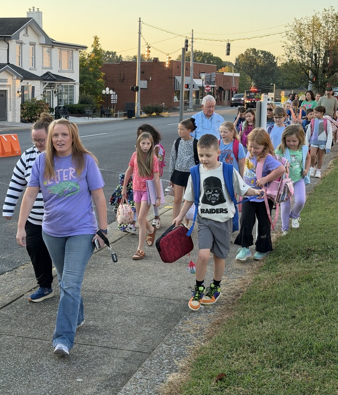 Group of walkers make their way up sidewalk for International Walk to School Day