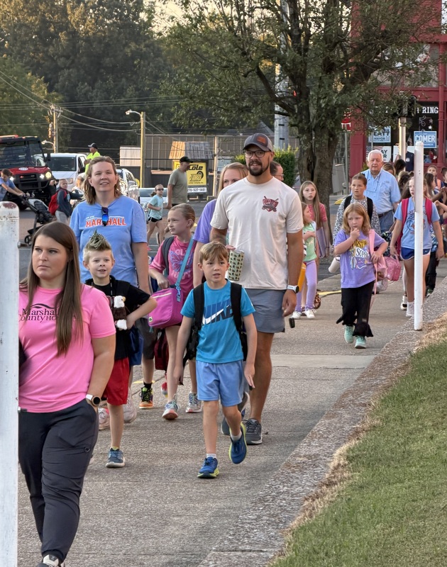 Group of walkers make their way up sidewalk for International Walk to School Day