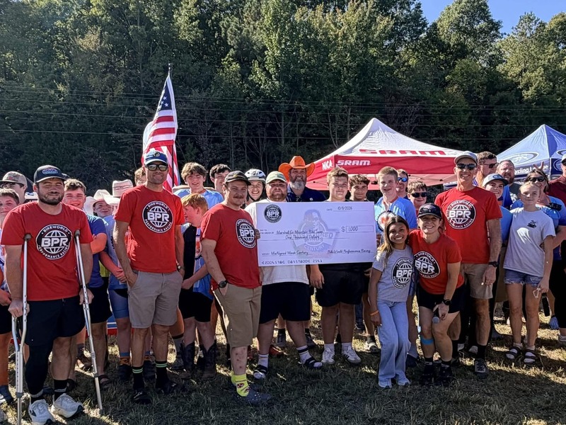 Marshall and Livingston mountain bikers holding up cardboard check