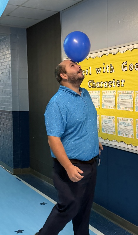 SMES staff member balancing blue balloon on forehead
