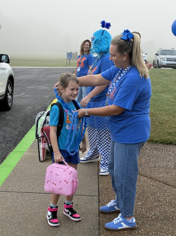 SMES students getting out of car and being give blue bands and leis