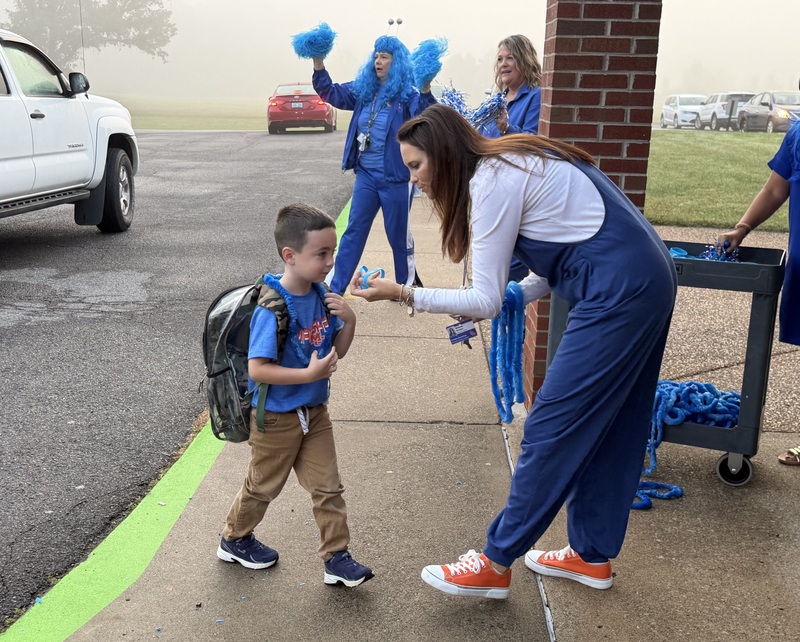 SMES students getting out of car and being give blue bands and leis