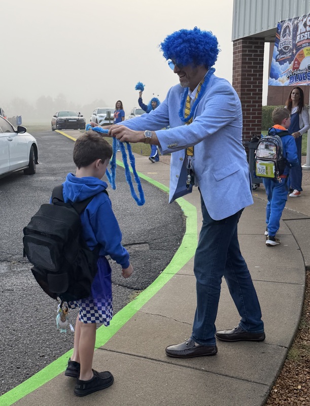 SMES students getting out of car and being give blue bands and leis