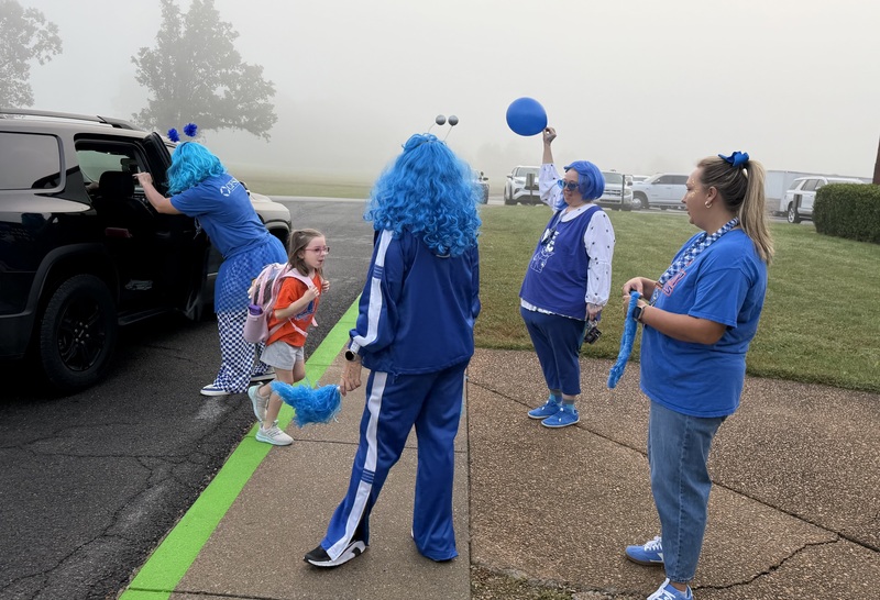 SMES students getting out of car and being give blue bands and leis