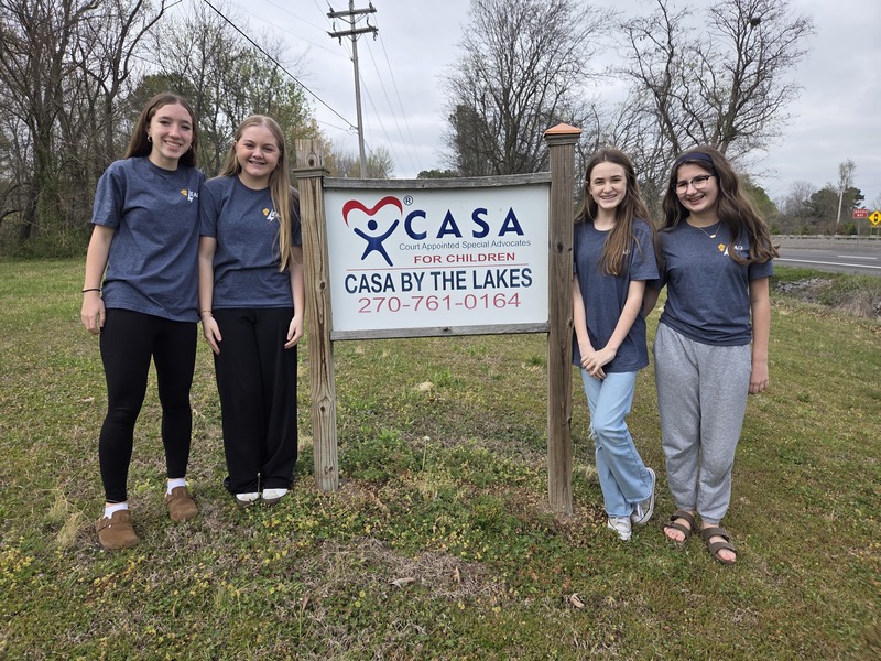 NMMS students delivering backpacks (in front of CASA by the Lakes sign)