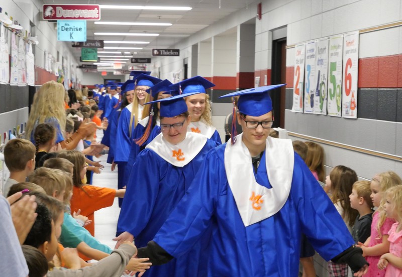 Seniors walking through BES with cap and gown