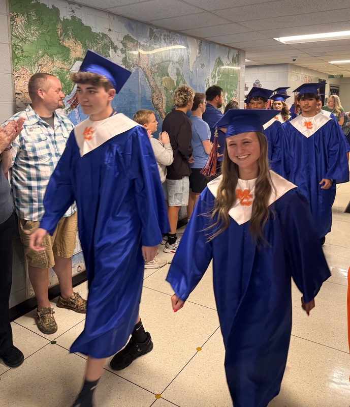 Seniors walking throug SES in cap and gown