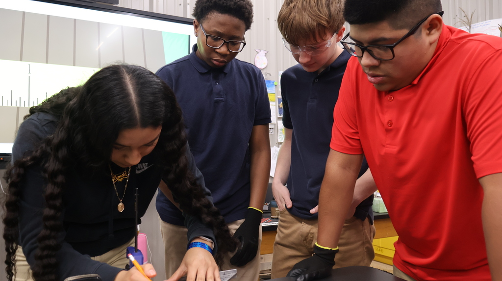 A student using a tape measure as other students observe.