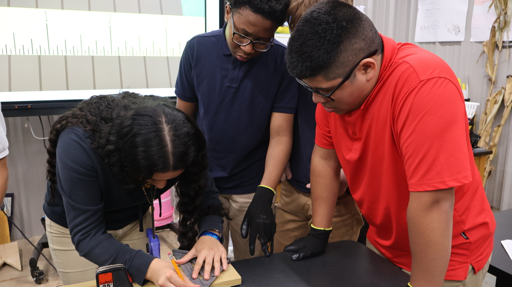 A student using a tape measure as other students observe.