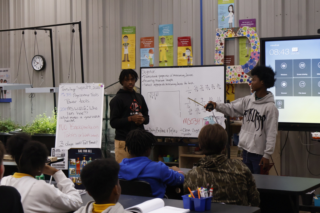 Electrical Students teaching agriculture students about using a tape measure accurately. 