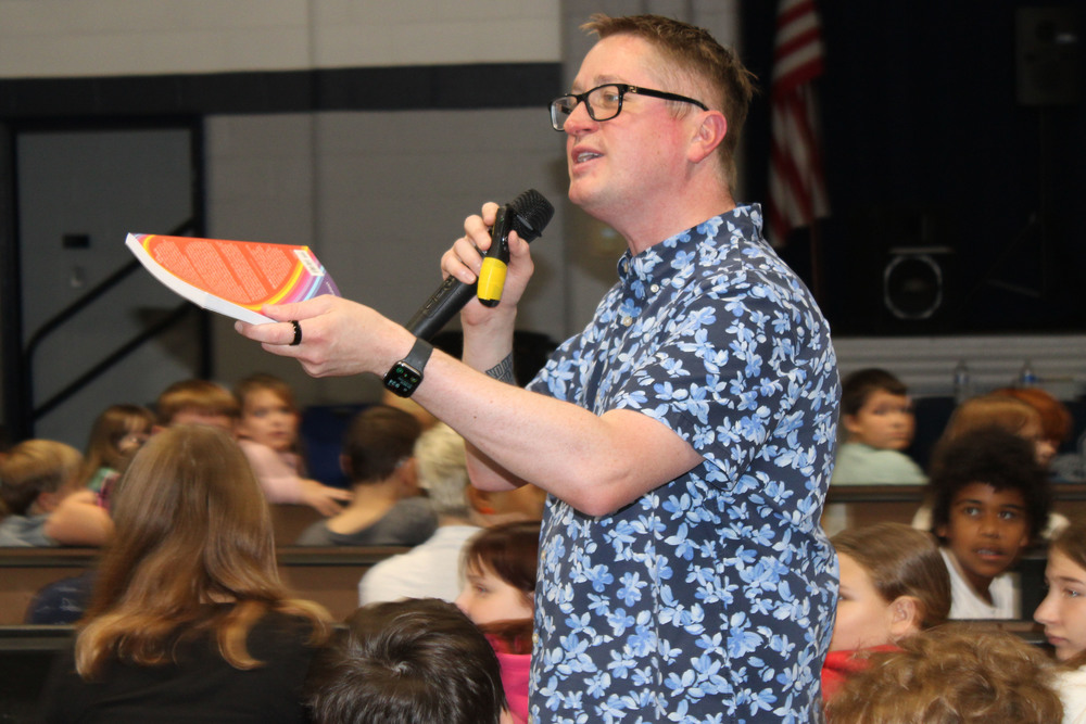 John Schu talking to students during an assembly.