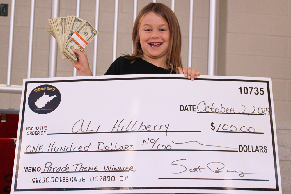 Ali poses with her oversized check and the bundle of 100, one-dollar bills she won.