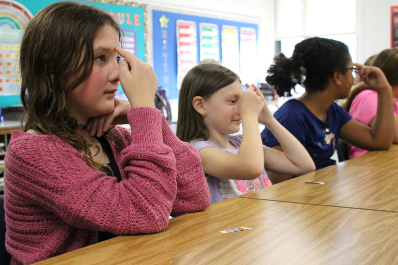 Pictured from left: Ember Woolley, Mackenzie Kent and Zuri Alford try “Calm Cape.” This technique, used to help block stress and worrying, is done by gently pressing the spot between the eyebrows.