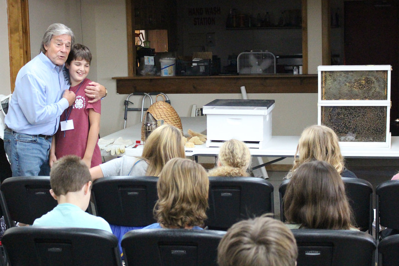 From left: Master Beekeeper Steve Roth has a Hilltop Elementary 5th grader help him demonstrate how honeybees use pheromones to communicate with each other and manage their colony.