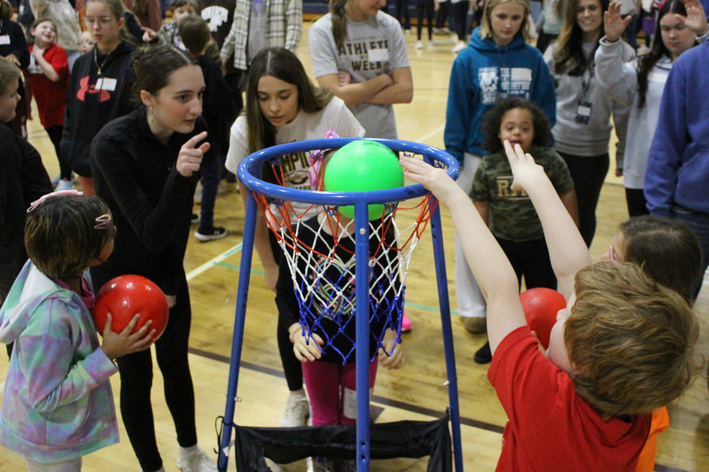 Student athletes and peer tutors play basketball.