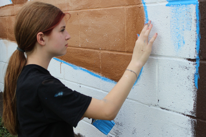 Middle school students paint a mural.
