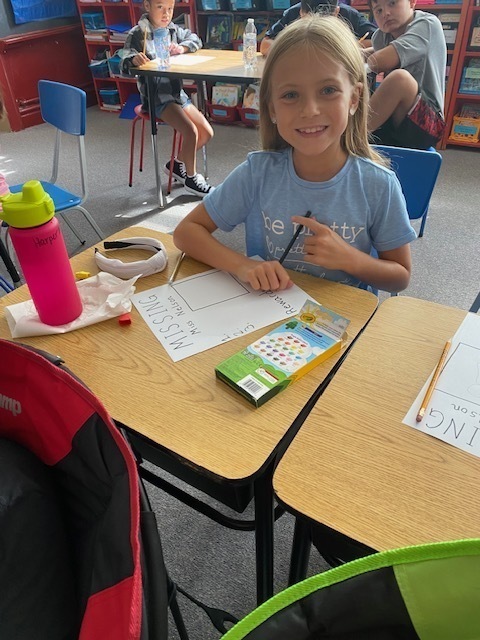 girl smiling while writing on paper