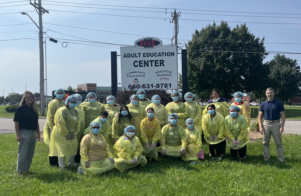students posing for photo in nursing yellow scrubs and blue masks