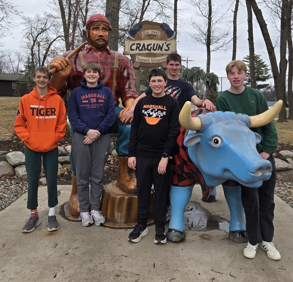Group of young men standing either a large man statue and a blue bull statue.